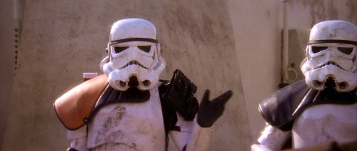 A sandtrooper commander, orange pauldron on shoulder, waves off a landspeeder. Star Wars (1977)